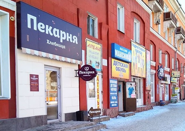 Увешанное рекламой здание на проспекте Красноярский Рабочий